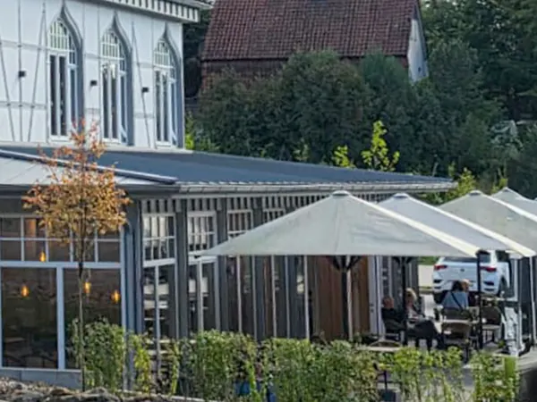 Die überdachte Terrasse mit Sonnenschirmen und Sitzgelegenheiten.
